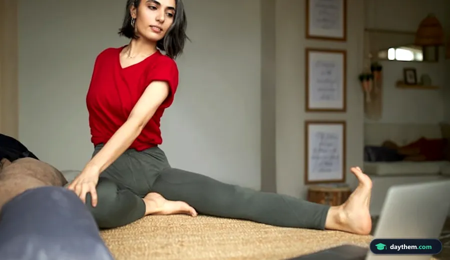 Phụ nữ tập thể thao đang ngồi giãn cơ trên sàn và xem hướng dẫn trực tuyến trên máy tính